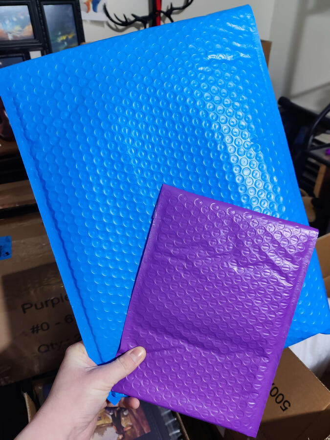 Photo of the bubble mailers for the zine. Large mailers are blue, small mailers are purple.